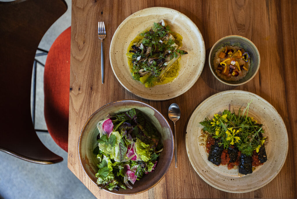 From left, Saintly Greens with red wine vinaigrette; leeks with mushrooms; stuffed collard greens with beet merges, tomato sauce and sunflower seeds; and rice pudding with baba au amaro and spring citrus at Little Saint in Healdsburg. (Chad Surmick / The Press Democrat)
