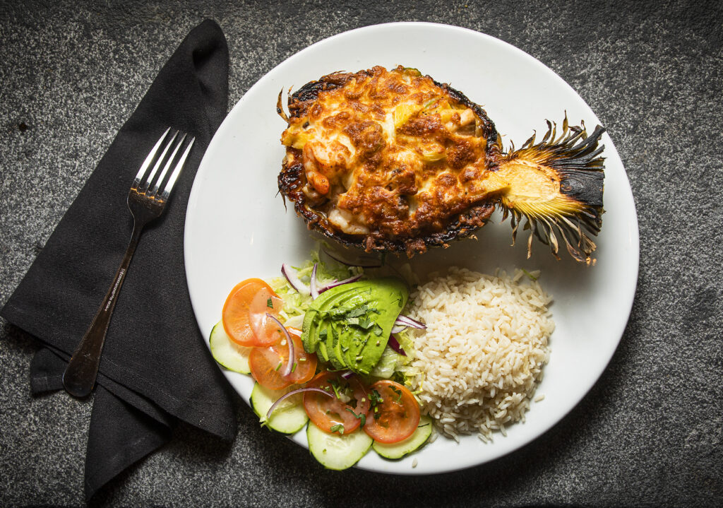 Piña Rellena is a pineapple filled with seafood with cheese on top and finished in the wood oven at Pezcow in Windsor on Friday, April 1, 2022. (John Burgess/The Press Democrat)