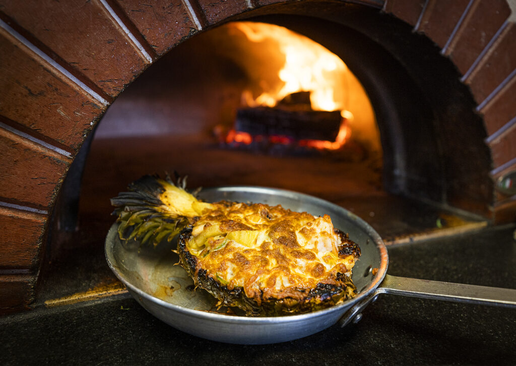 Piña Rellena is a pineapple filled with seafood with cheese on top and finished in the wood oven at Pezcow in Windsor on Friday, April 1, 2022. (John Burgess/The Press Democrat)