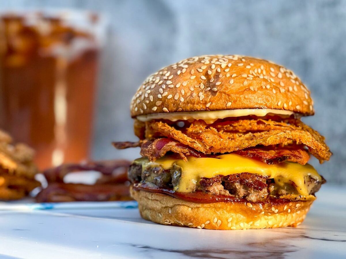 Chuck/brisket blend, house-smoked bacon, crispy onion rings, American cheddar, garlic chili aioli and Kansas City BBQ sauce on a brioche bun from Lunch Box. (Courtesy of Lunch Box)