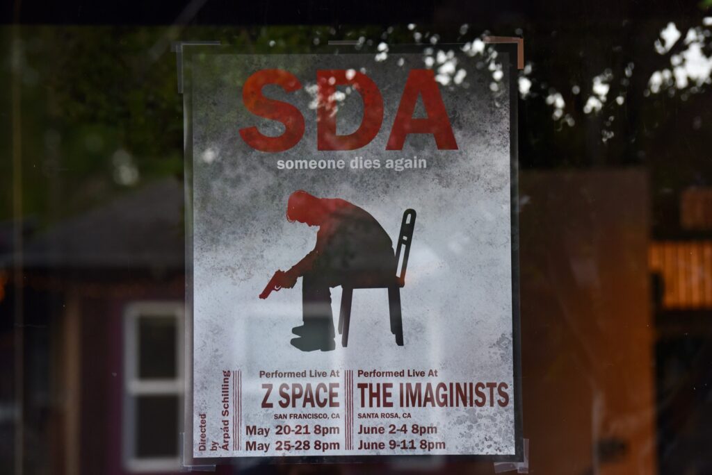 The poster for “S D A (Someone Dies Again),” a new work by Hungarian Director Árpád Schilling that focuses on the role that gun violence play in American society at The Imaginists theater in Santa Rosa, Calif., on Monday, April 30, 2022. (Erik Castro/For The Press Democrat)