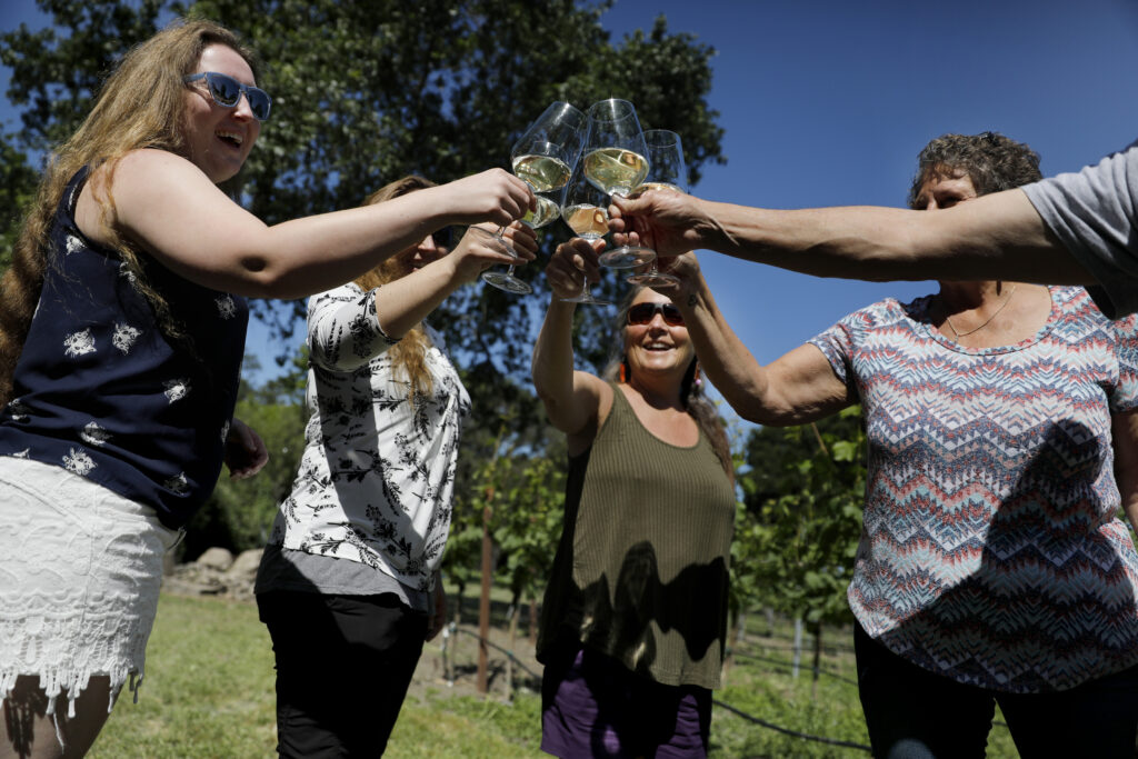 Owner Pam Willis, right, does a cheers with guests visiting from Anchorage, Alaska during a vineyard tour at The Gables Wine Country Inn in Santa Rosa, Calif., on Sunday, May 1, 2022. (Beth Schlanker/The Press Democrat)