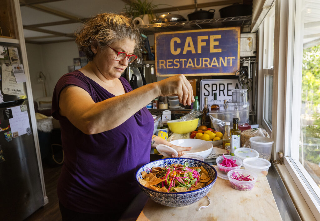 Cristina Topham, owner of Spread Kitchen. in Sonoma, tops off her Fattoush salad with a sprinkle of Za'atar in her Sonoma home kitchen. (John Burgess/The Press Democrat)