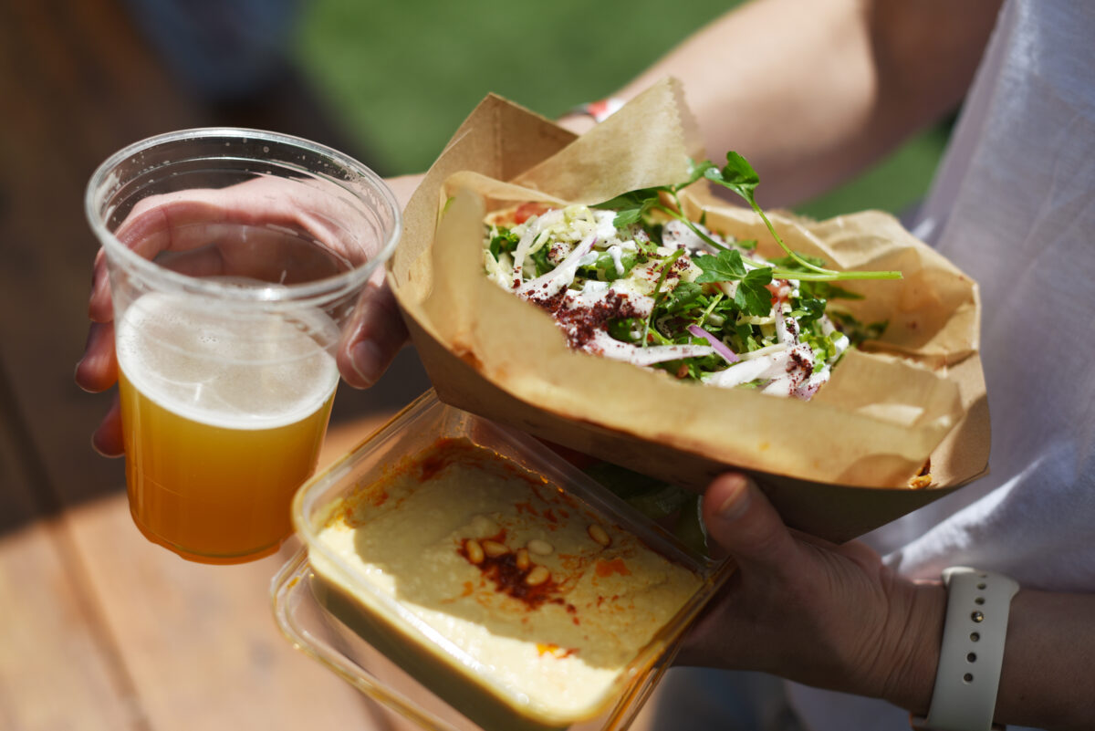 Cindi Lucas, of Boston, has a chicken gyro kebab with hummus and a beer made by Tarla Mediterranean Bar + Grill on Friday, May 27, 2022, at BottleRock Napa Valley in Napa. (Erik Castro / For The Press Democrat)