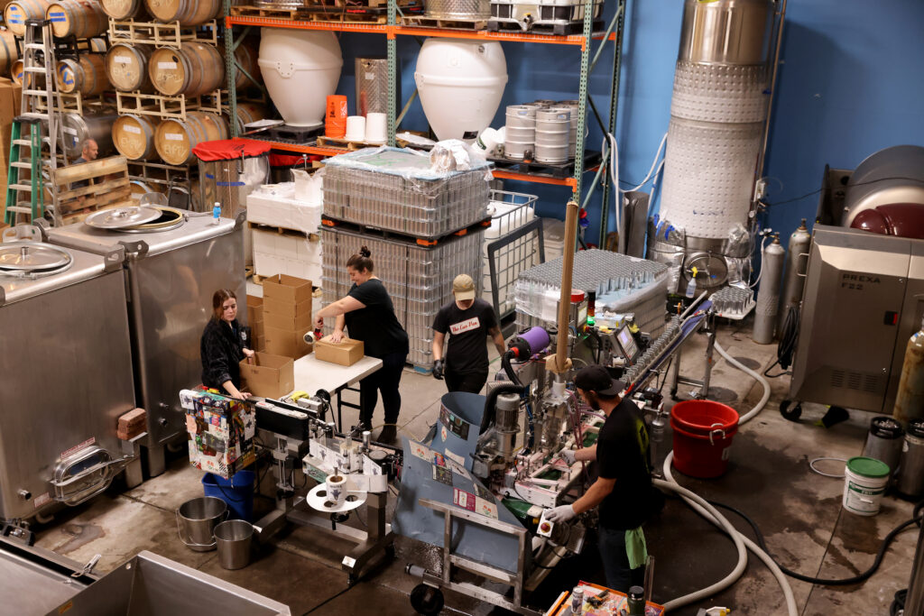 Two Shepherds employees box sparkling piquette as its canned by employees from The Can Van, a mobile canning service, in Windsor, Calif. on Tuesday, May 31, 2022. (Beth Schlanker/The Press Democrat)