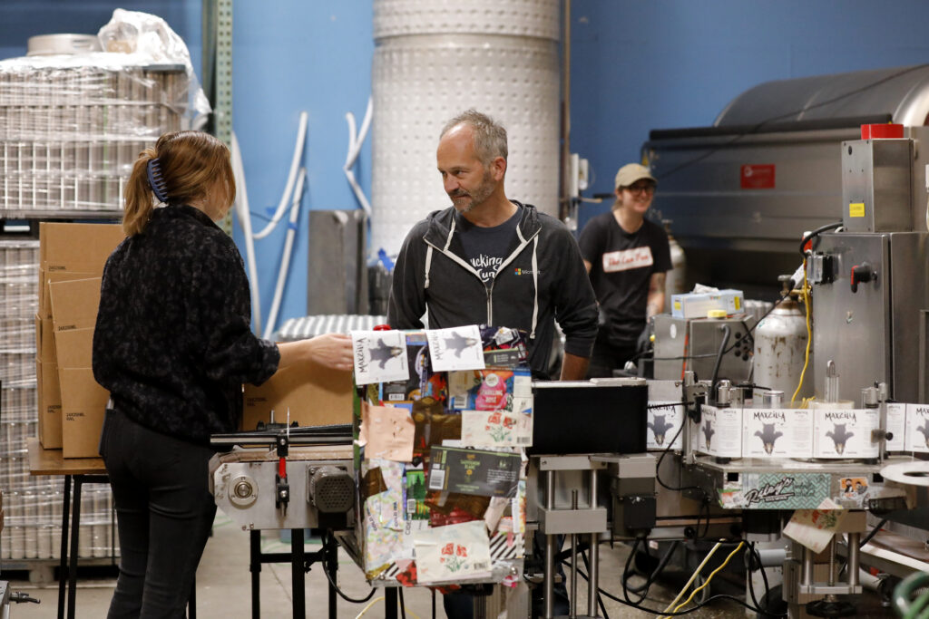 Winemaker William Allen talks with employee Josephine Marriner while they can sparkling piquette at Two Shepherds in Windsor, Calif. on Tuesday, May 31, 2022. (Beth Schlanker/The Press Democrat)