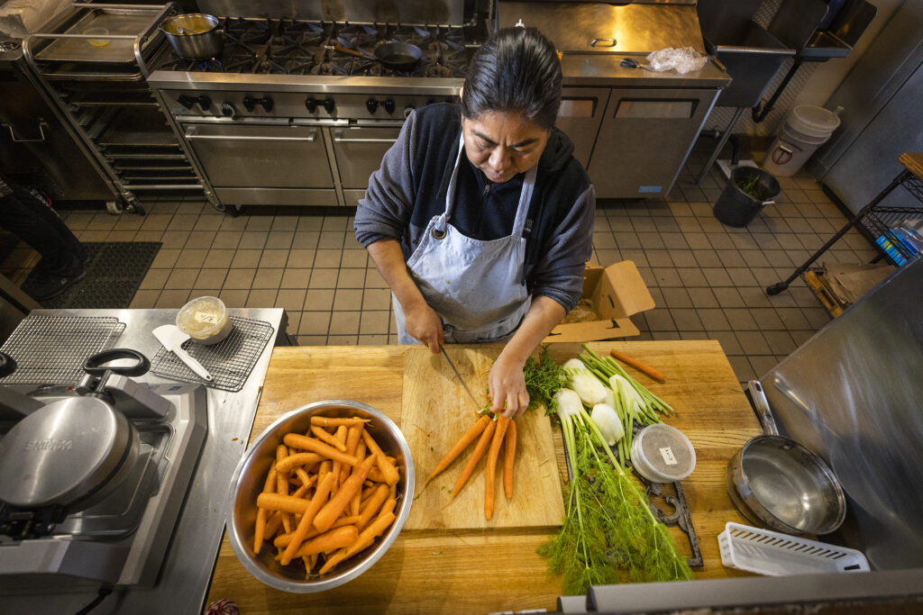 Malena Cortez trims the greens off the tops of carrots before juicing them at the Naked Pig in Santa Rosa. The tops are destined for a compost bucket at her feet, then into owner Dalia HernandezÕs home compost. (John Burgess/Sonoma Magazine)