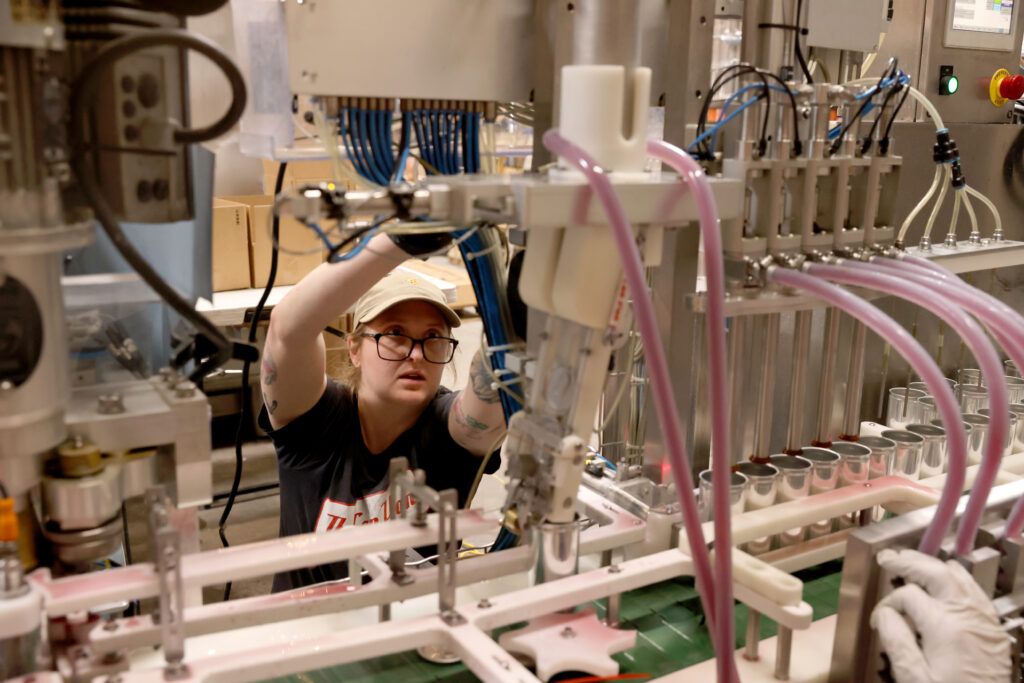 Danielle Looney, an employee of The Can Van, a mobile canning service, makes an adjustment to the production line at Two Shepherds in Windsor, Calif. on Tuesday, May 31, 2022. (Beth Schlanker/The Press Democrat)