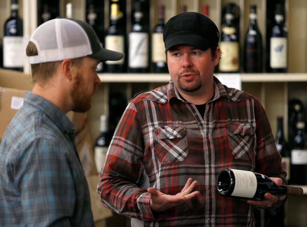 Bottle Barn wine specialist Jordan Wardlaw, right, discusses the selection of French wines with vineyard manager Tyler Hammond at Bottle Barn in Santa Rosa, California. (Alvin Jornada / The Press Democrat)