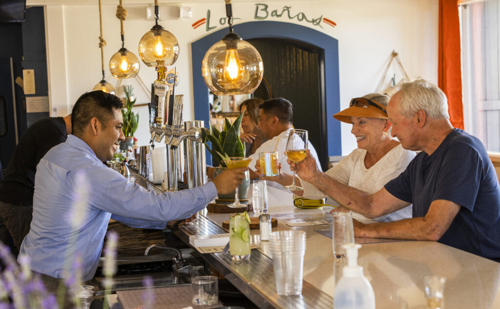 Server Anibal Montoya, left, with guests Mary Louise Fleming and Mike Diger at Kina’s Kitchen & Bar in Sonoma. (John Burgess / The Press Democrat)