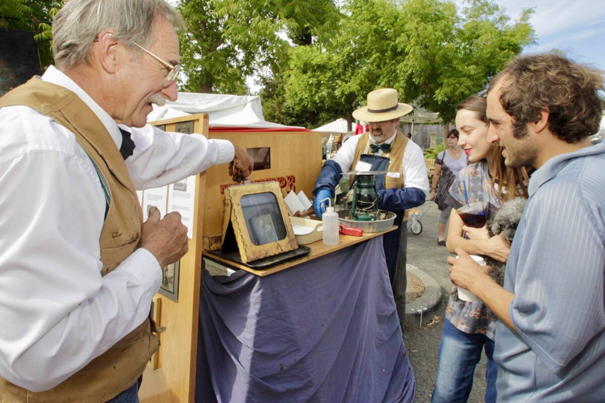Bruce Morton showing Sam Rifkin and Rachel Burrow how their tintype is developed at the Petaluma Antique Faire on September 27, 2015, in downtown Petaluma. (Jim Johnson/For the Argus-Courier)