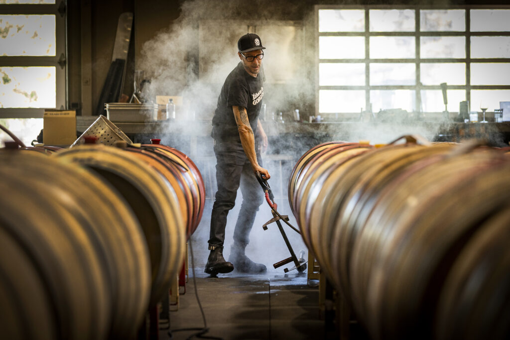 Monte Rio Cellars owner/winemaker Patrick Cappiello cleans barrels after pumping over his wines in the Pax Wines' winemaking facility at The Barlow in Sebastopol. (John Burgess/Sonoma Magazine)