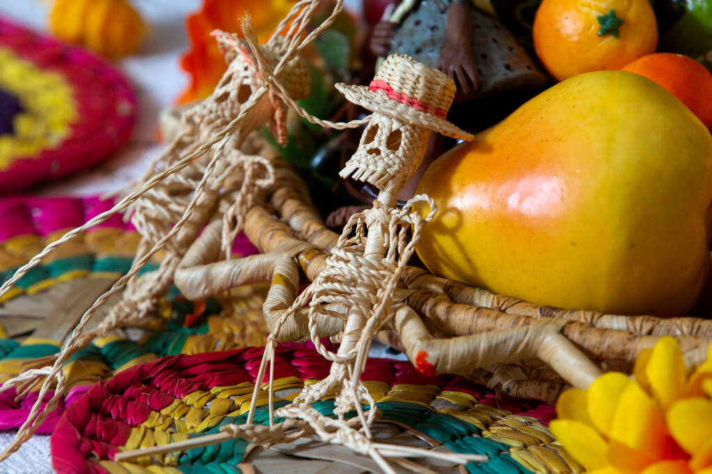 Esqueletos hechos de hilo se sientan junto a un plato de frutas en el altar del Día de los Muertos creado por el artista Peter Pérez en su casa en Santa Rosa el jueves 22 de octubre de 2020 (Foto: Alvin A.H. Jornada / The Press Democrat)