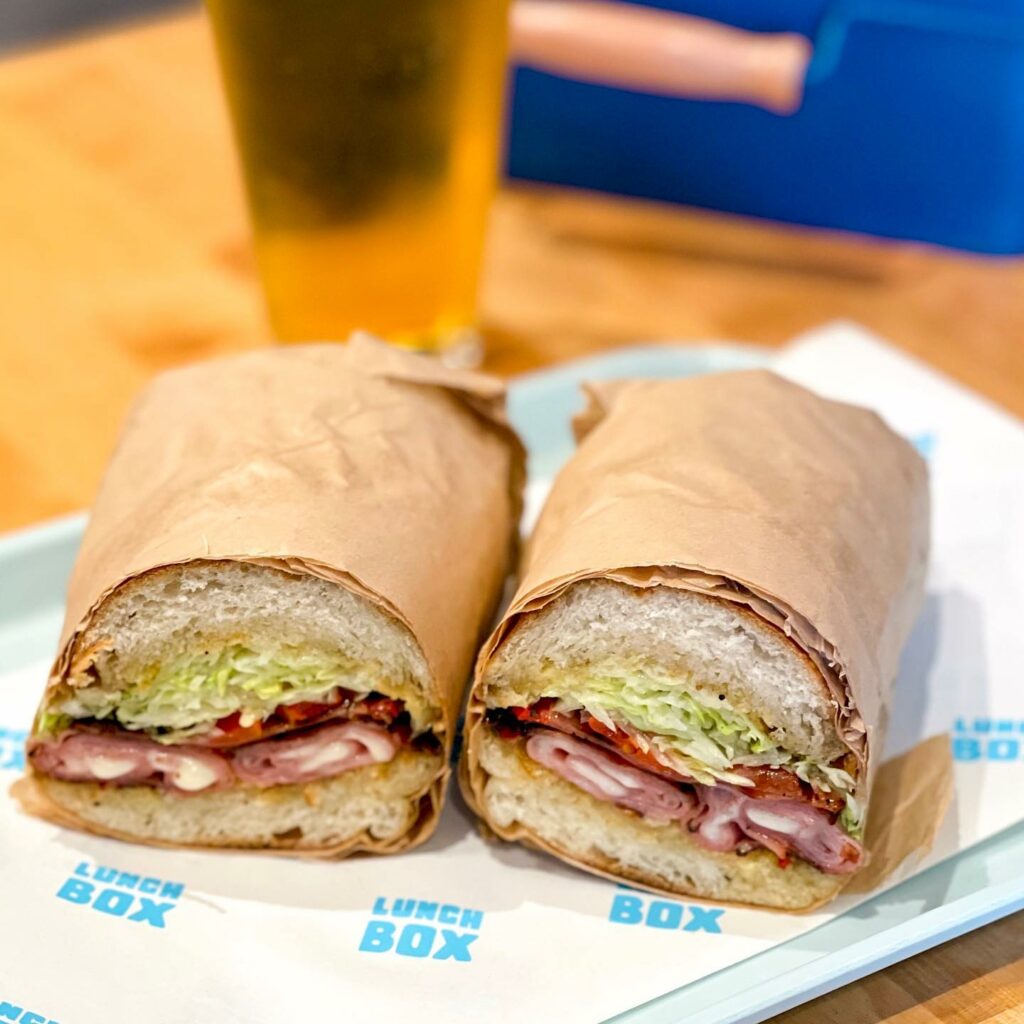 Griddled Mortadella sandwich from Lunchbox with sliced mortadella, provolone, mama lil’s, shredded iceberg, and garlic chili aioli on a sourdough hoagie. (Courtesy of Lunchbox)