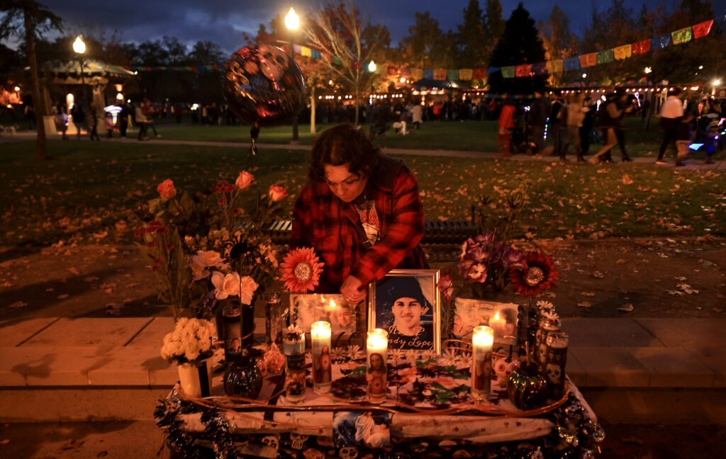 Aubrey Martin of Santa Rosa puts the finishing touches on an altar for her children (both deceased) Diego and Bridgette next to Andy Lopez, Saturday, Oct. 30, 2021 during Windsor's Día de los Muertos event. Martin's daughter went to school with Lopez. (Kent Porter / The Press Democrat)