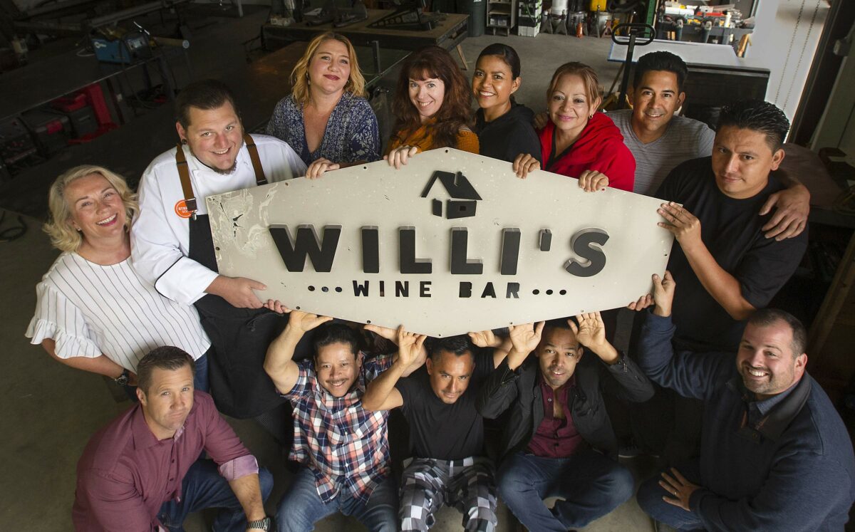 Former employees of Willi's Wine Bar hold the old burnt sign being readied to install in the new location in the Town and Country Shopping Center in northeast Santa Rosa. The crew worked at other Stark's restaurants until the new location opened. (John Burgess / The Press Democrat)