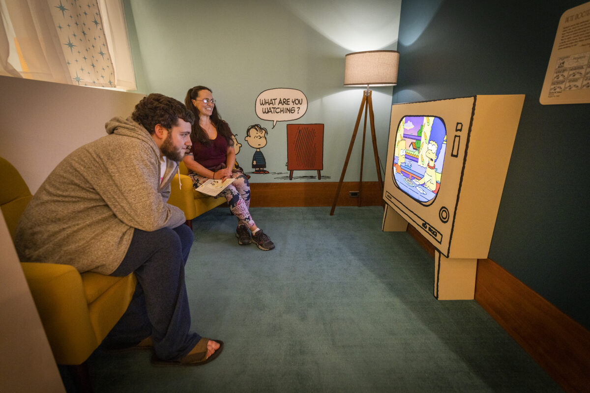Gabriel Schamber, left, and Sara Frank watch a piece about the effect Peanuts had on other TV shows at the Charles M. Schulz Museum and Research Center November 3, 2022. (John Burgess/The Press Democrat)