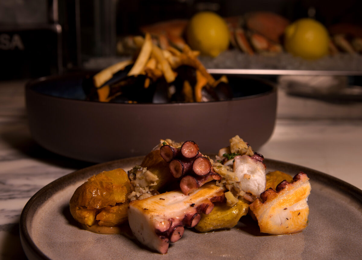 Spanish Octopus a-la-plancha with Shitake Dressing, Crispy Fingerlings, and Black Garlic Aioli, also showing Moules Marinieres in the background, at Oyster, a new restaurant in The Barlow, Monday, Nov. 7, 2022, in Sebastopol. (Darryl Bush / For The Press Democrat)