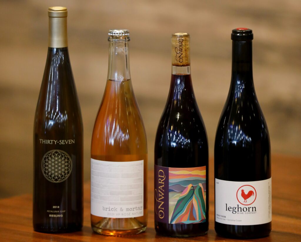 (From left) Thirty-Seven Wines, 2018 Riesling, Petaluma Gap, Sonoma County $25.99, Brick & Mortar Wines, 2021 VP Rose Nature. $24.99, Onward Wines, Nouveau Style, Whole Cluster Zinfandel, 2021 $21.99 and Leghorn Wine Company, 2018 Petaluma Gap Pinot Noir $29.99 for sale at Wilibees Wine and Spirits in Santa Rosa, Calif. on Wednesday, November 2, 2022. (Beth Schlanker/The Press Democrat)