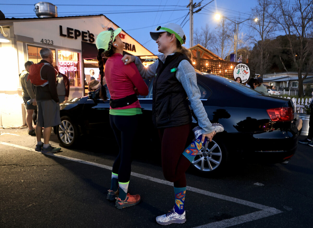 Giuliana Dibiazza, from Santa Rosa, and Oksana Krishna form Petaluma stretch out during Healdsburg Running Co's run and a meal afterward at Lepe's Taqueria in Santa Rosa, Thursday, Feb. 9, 2023. (Kent Porter / The Press Democrat) 2023