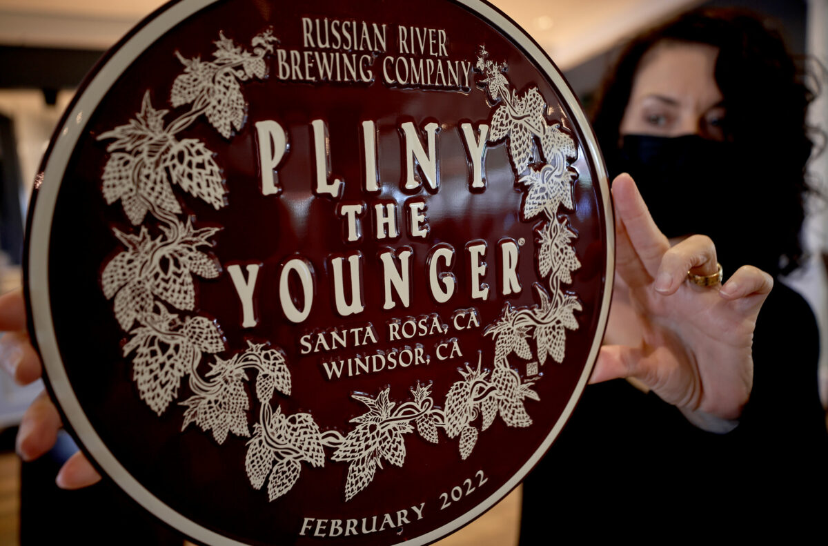 Natalie Cilurzo, co-owner of the Russian River Brewing Company in Windsor, displays a wall plaque of their popular Piny the Younger, Wednesday, Jan. 12, 2022. (Kent Porter / The Press Democrat) 