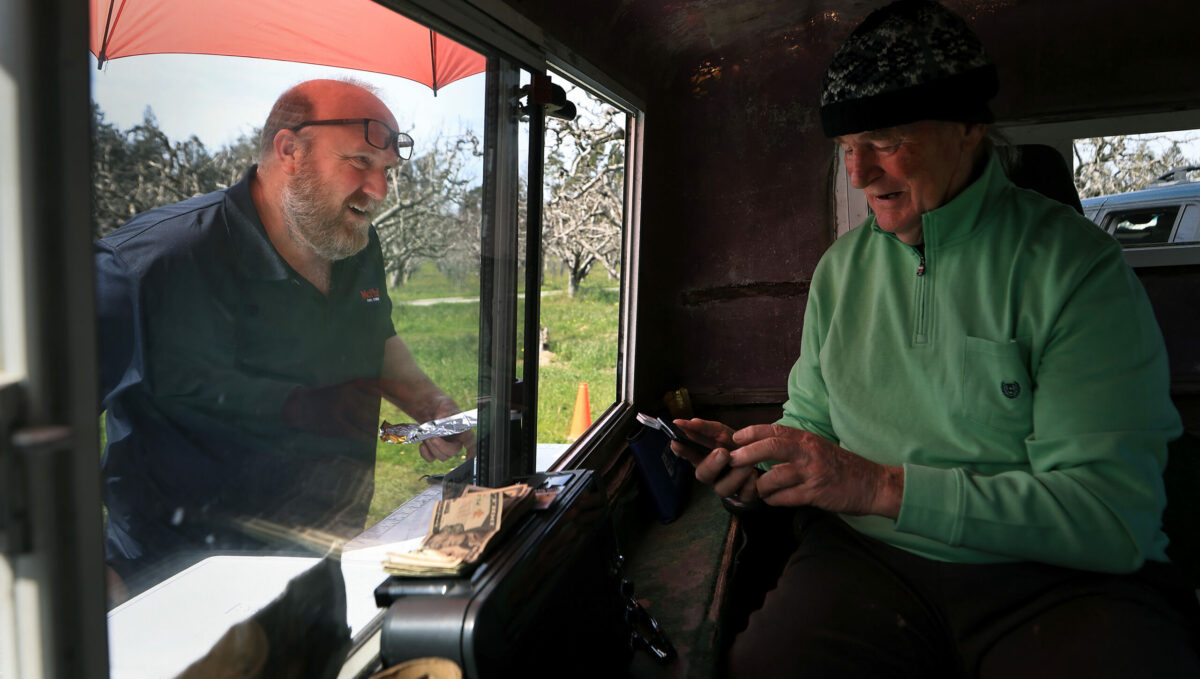 Greg Brummet rings up a purchase for a customer at Brummet's roadside Samnzar Smoke Shack, a small portable trailer towed by his truck, on Highway 12, just west of Sebastopol, Friday, March 17, 2023. (Kent Porter / The Press Democrat) 2023