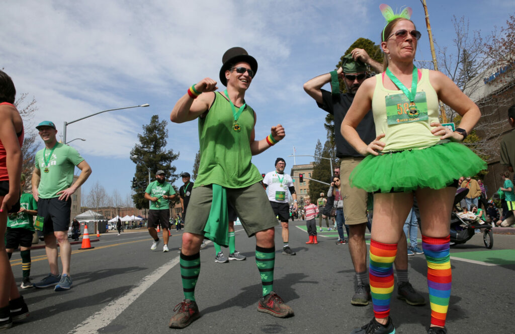 Dr. Galen Hegarty, center, and Kimberly Beltran, right, wait at the finish line for others in their group during the St. Patrick's Day 5K on Santa Rosa Ave. near Old Courthouse Square in Santa Rosa on Sunday, March 13, 2022. (Beth Schlanker/The Press Democrat)