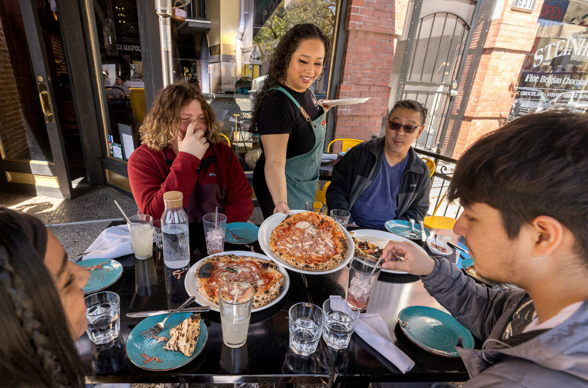Taylor De Angelis serves pizza to guest on the 4th Street patio at L'Oro di Napoli in downtown Santa Rosa March 24, 2023. (John Burgess/The Press Democrat)