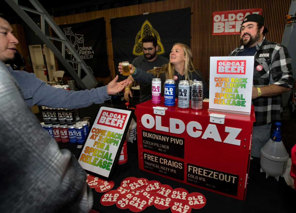 Cassie Mcmillen, of Old Caz Beer, hands beer to an attendee as Rob Saccuzzo, tap room manager at Old Caz Beer, right, looks on during the 26th annual Battle of the Brews, at the Sonoma County Fairgrounds in Santa Rosa. (Darryl Bush / For The Press Democrat)
