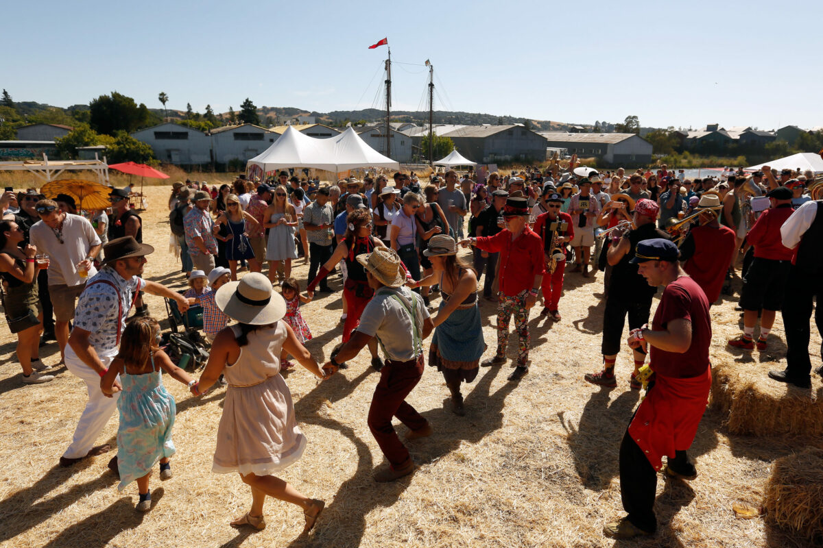 People dance together while the Hubbub Club performs during Rivertown Revival at Steamer Landing Park in Petaluma, California, on Saturday, July 14, 2018. (Alvin Jornada / The Press Democrat)