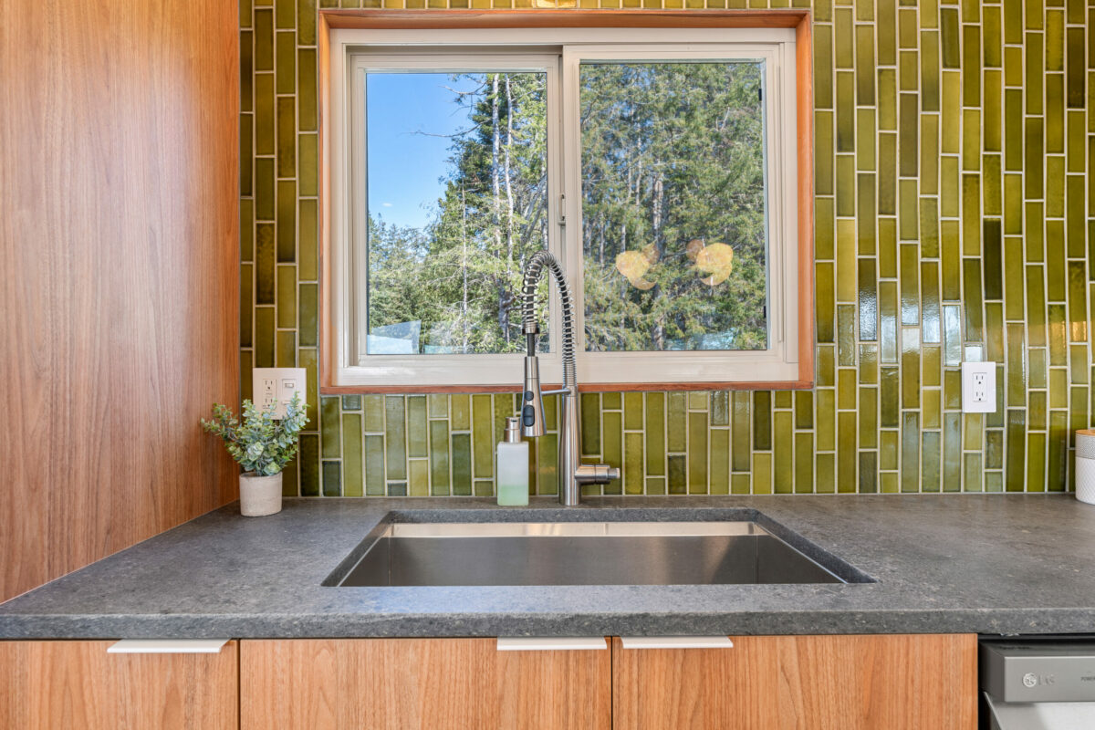 A vertical tile backsplash—made of handmade tiles from Heath Ceramics— provides a crisp contrast to the warm wood finishes. (Bill Oxford Photography)