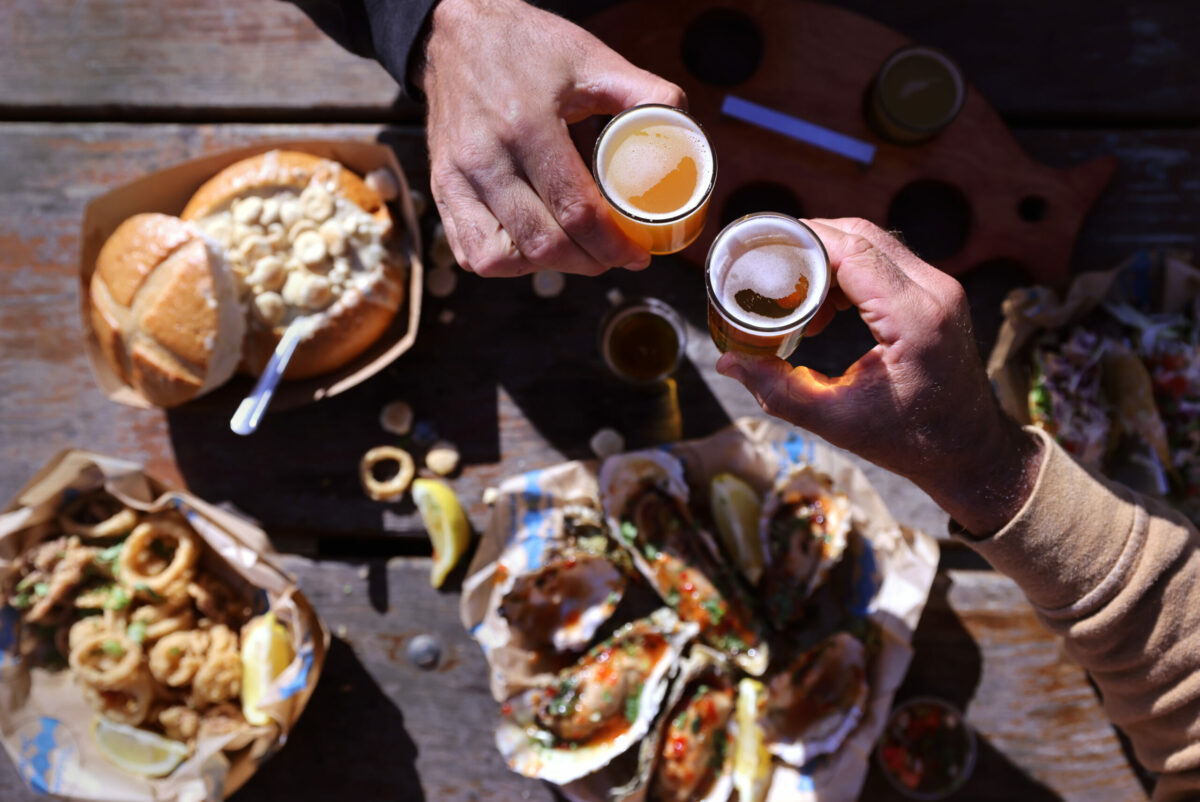 Justin Reeb and Mitch Kotok, right, cheers their beer at Fishetarian Fish Market in Bodega Bay on Tuesday, June 28, 2022. (Beth Schlanker/The Press Democrat)
