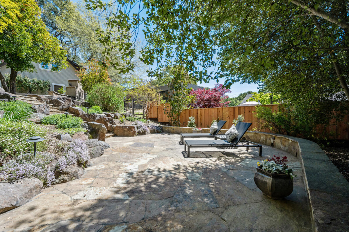 Different levels of paved patios are surrounded by mature gardens. (Open Homes Photography)