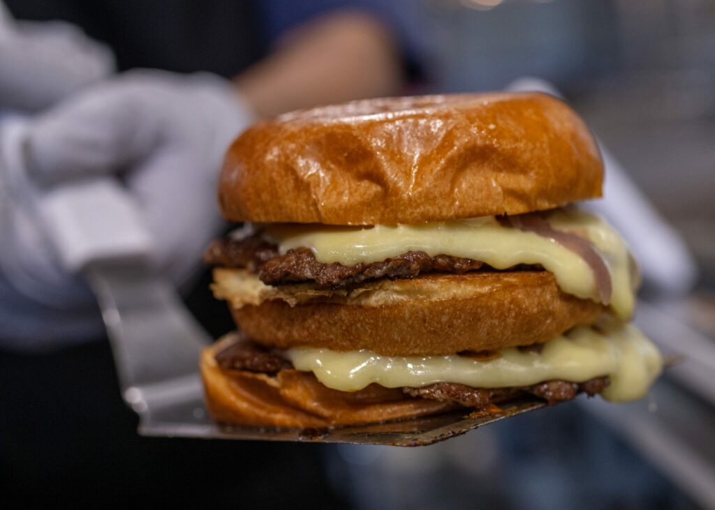 Iggy’s Organic Burgers with duck fat and beef patty, buttery brioche, organic American cheese, ketchup, mustard, onions caramelized with a secret sauce, and pickles are served on the plaza, Friday in Downtown Healdsburg June 30, 2023. (Chad Surmick / The Press Democrat)