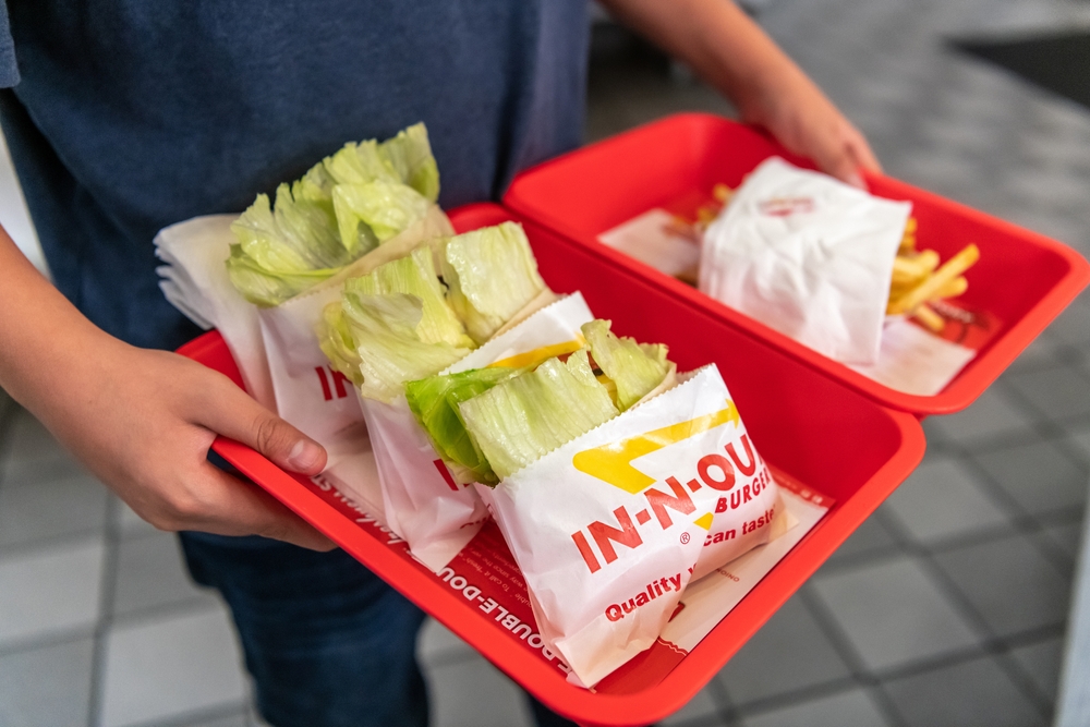Customer holding a tray with lettuce-wrapped burgers at an In-N-Out restaurant in San Francisco. (Shutterstock)