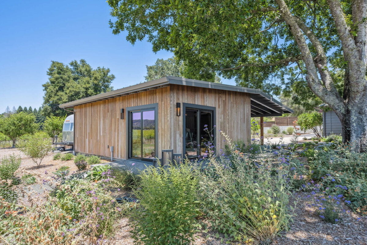 A handsome “barn” with vertical stained siding and glass sliders can serve as a home gym or an office with a view. (Open Homes Photography)