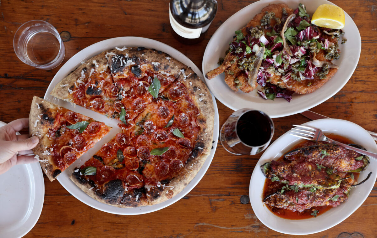 Pepperoni pizza with basil and drizzled with spicy honey, the pork chop Milanese with anchovies and chicories, top, and the meatball stuffed peppers in a braising sauce with a chili crisp, bottom, at Ciccio in Yountville, Monday, July 10, 2023. (Beth Schlanker / The Press Democrat)