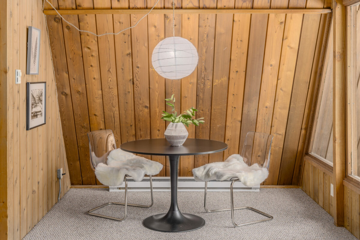 A modern table, lamp and ghost chairs are right at home against the wood-paneled walls. (Paul Rollins)