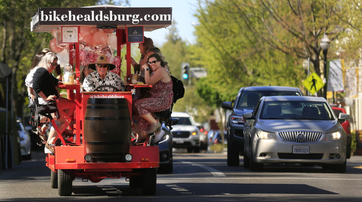 Bike Healdsburg.com driver Tim Buckner, uses the pedal power of 12 women as they head to a winery in Healdsburg to celebrate a bridal shower, Saturday, April 10, 2021. Husband unwise owners owner Jessica and Chris Pilling said the pandemic closed their business nearly 3/4 of the year. As the economy begins to open up, their bookings have increased. (Kent Porter / The Press Democrat) 2021