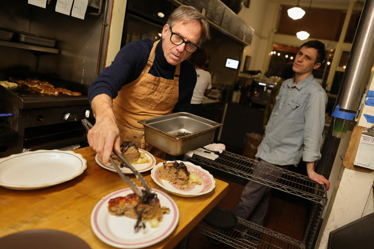 Chef Mark Malicki prepares plates of Stemple creek meatloaf, duck fat fried potatoes, black chanterelle butter bath & greens, while Jack Reed waits to serve them to customers, at de Havilland in Petaluma on Friday, January 12, 2024. (Christopher Chung/The Press Democrat)