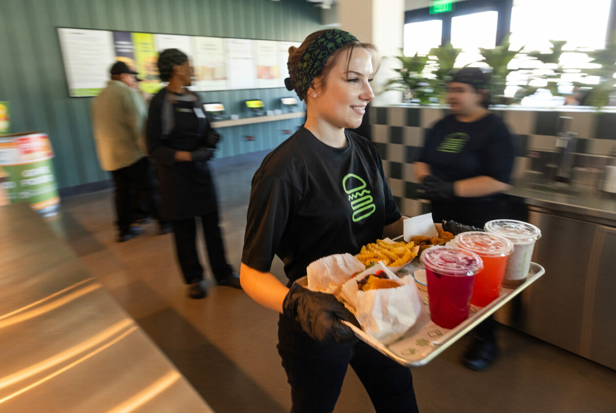New trainee Elie Woehrle delivers an order to a table at the first Shake Shack in Santa Rosa’s Montgomery Village Wednesday, February 28, 2024. (Photo by John Burgess/The Press Democrat)