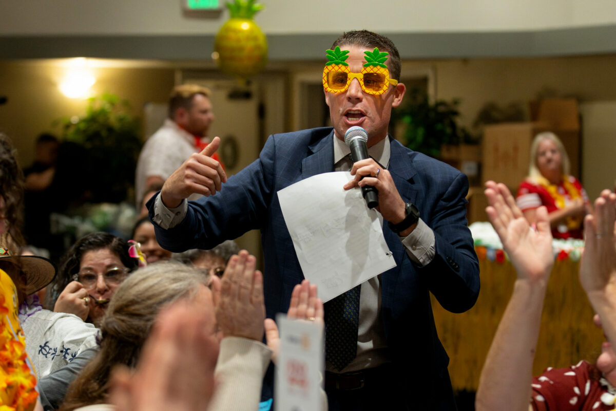 State Sen. Mike McGuire, wearing themed glasses acts as auctioneer for a benefit auction while people applaud during Russian River Rotary’s Hawaiian luau-themed 37th annual crab feed at Friedman Events Center in Santa Rosa, Saturday, Jan. 20, 2024. (Darryl Bush / For The Press Democrat)