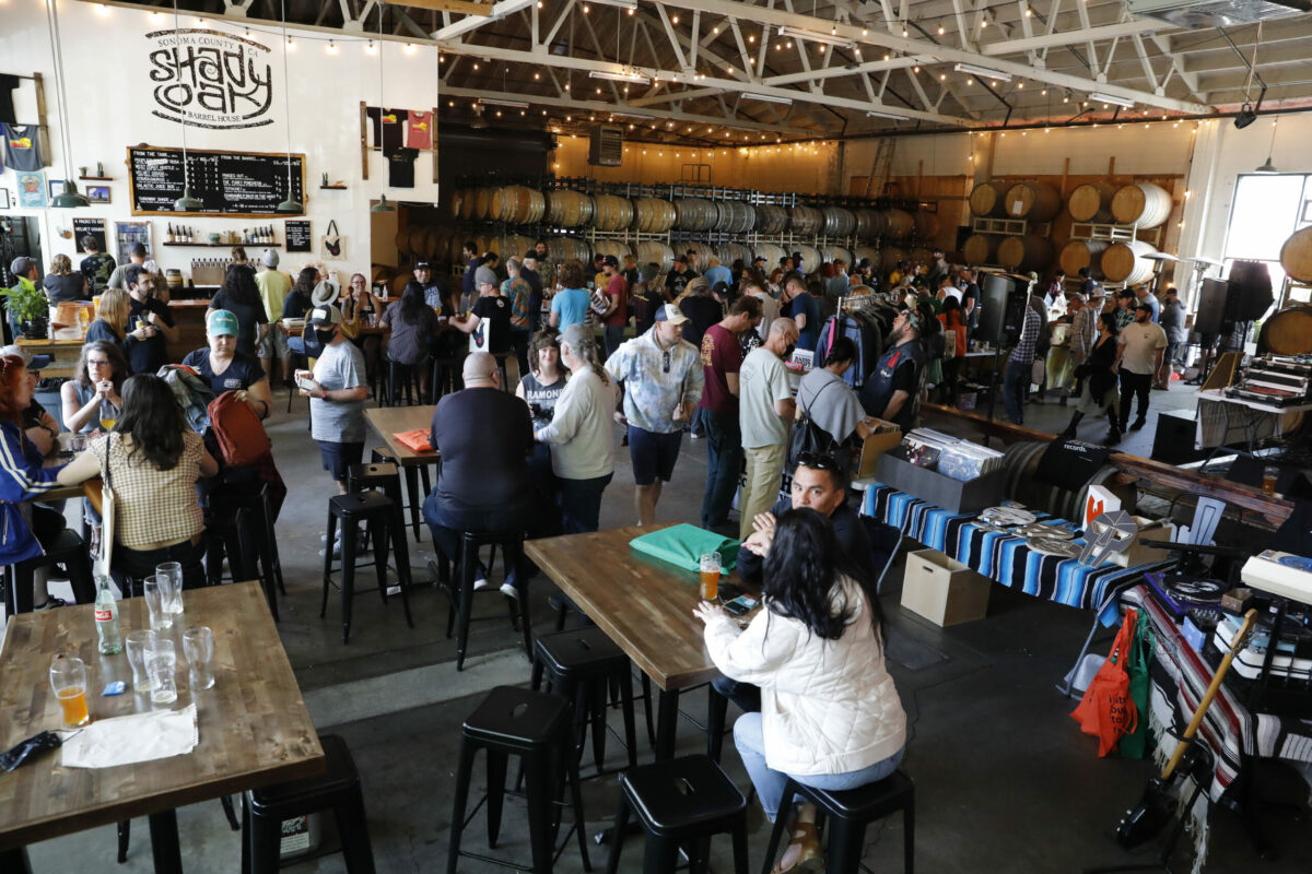 Patrons drink beer, listen to music and look through boxes of records during a record swap at Shady Oak Barrel House in Santa Rosa, Calif., on Sunday, April 10, 2022. (Beth Schlanker/The Press Democrat)