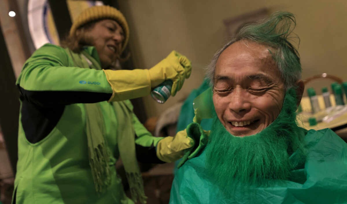 Norm Fujita gets green as Alex Rollins sprays biodegradable hairspray prior to the Healdsburgs St. Patricks Day Parade, Friday, March 17, 2023. Both are with the Healdsburg Rotary Club. (Kent Porter / The Press Democrat)