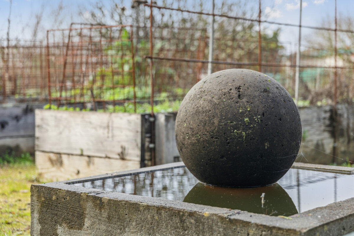 The property has a spherical stone fountain and raised garden beds. (Compass)
