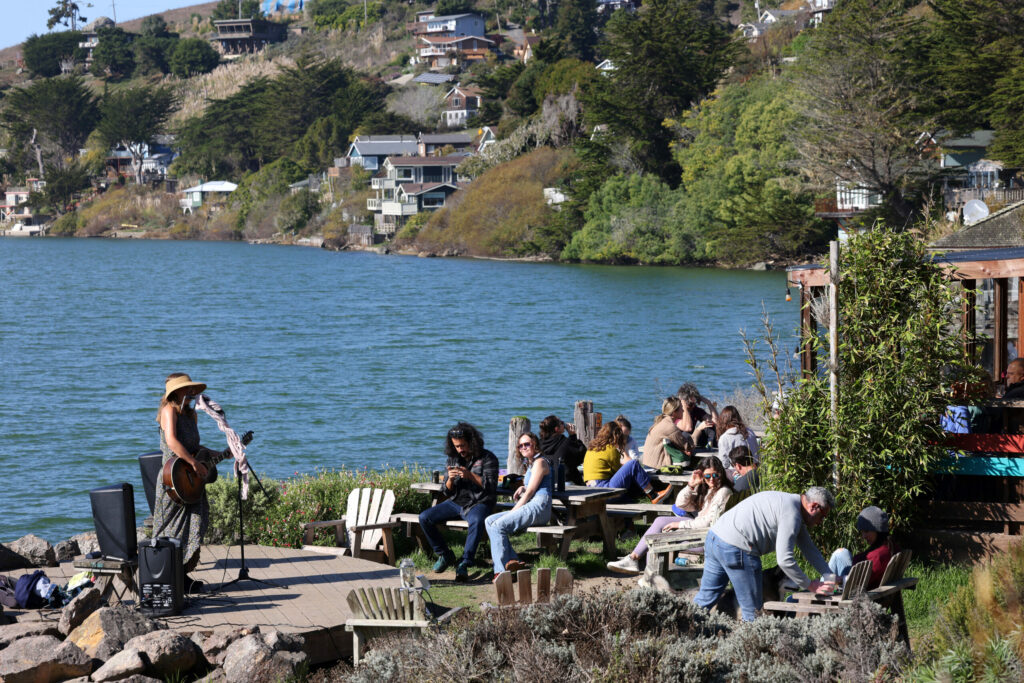 Customers listen to live music while they dine outdoors along the Russian River at Café Aquatica in Jenner, Sunday, Nov. 12, 2023. (Beth Schlanker / The Press Democrat)