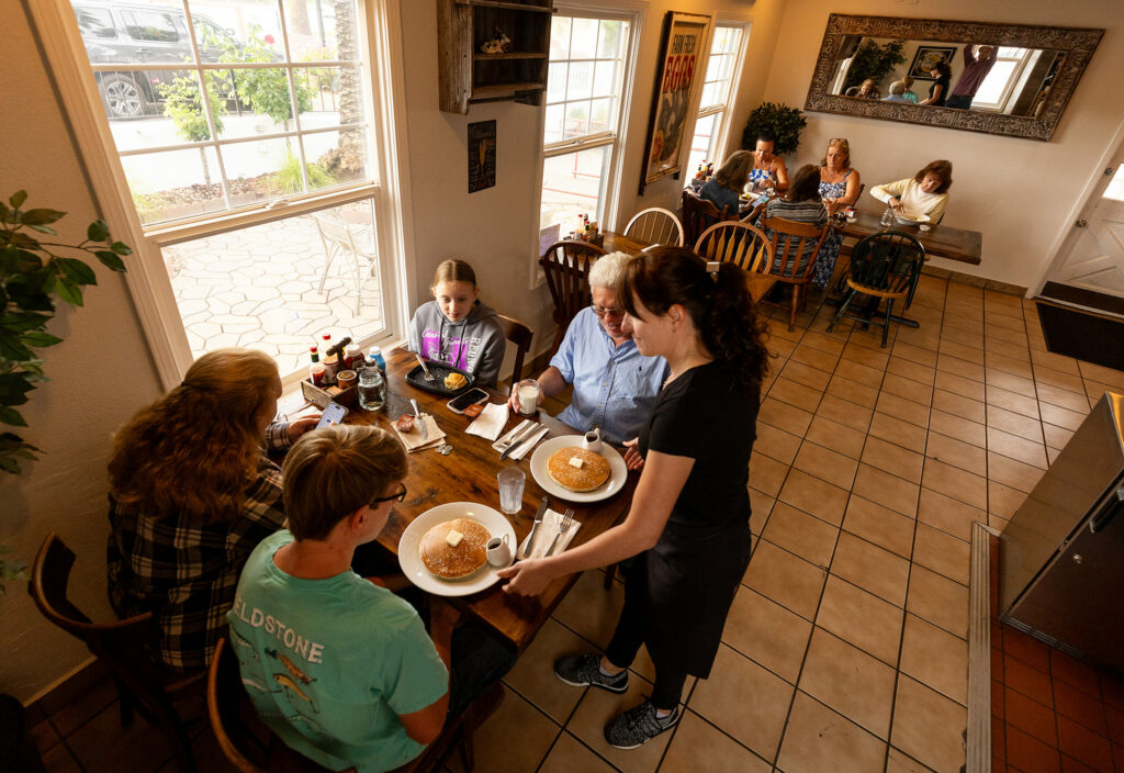 Paula Ledesma serves up pancakes to a family on a road trip from Georgia at the Verano Cafe Thursday, June 13, 2024 in Sonoma. (Photo by John Burgess/The Press Democrat)