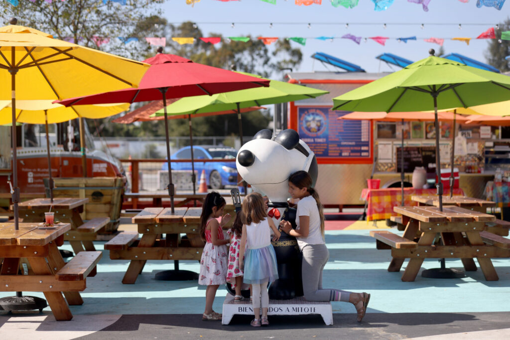 Girls gather around a Snoopy statue dressed as a mariachi band member at the Mitote Food Park in Santa Rosa, Calif. on Monday, July 25, 2022. (Beth Schlanker/The Press Democrat)