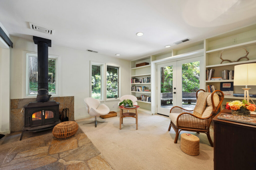 Built-in shelves, forest views and a wood burning stove give this room a cozy feel. (Open Homes Photography)