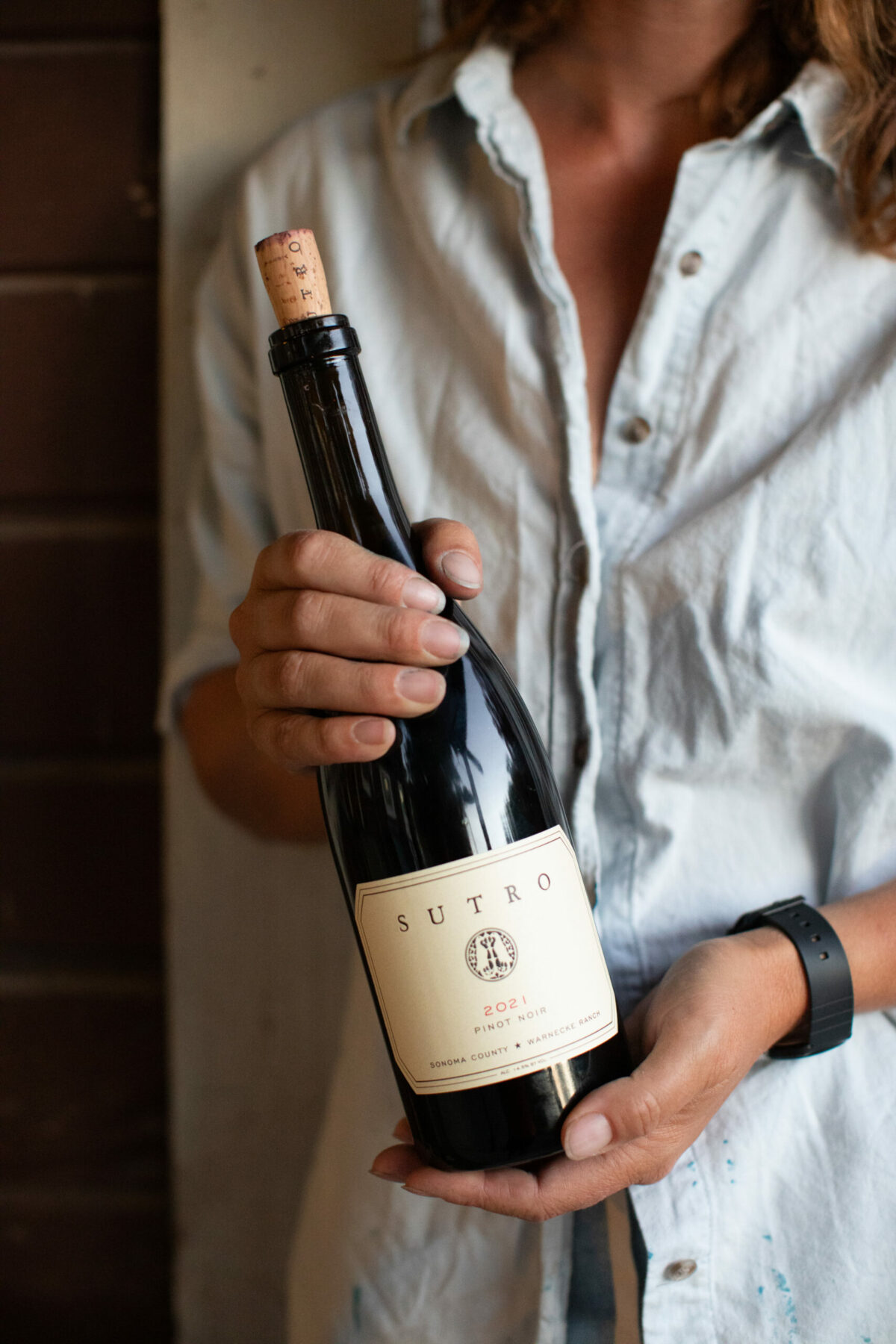 Alice Warnecke Sutro sets aside large-scale art projects during harvest but creates shorter pieces on the fly. Here, she holds a bottle from her own label, SUTRO Wine Co. (Liza Gershman/Sonoma Magazine)